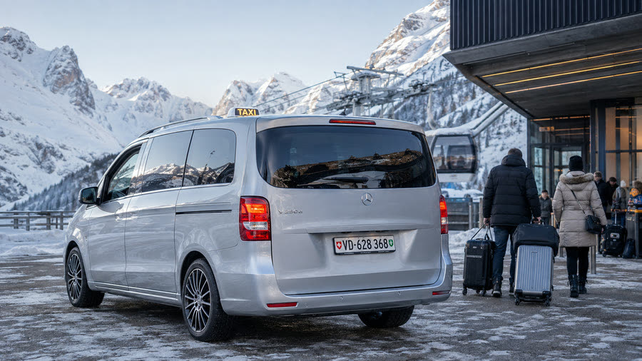 Taxi Mercedes Classe V TAXI 624 devant la gare du télécabine d'une station de ski, voyageurs et valises — transfert ski depuis Lausanne et Genève Aéroport