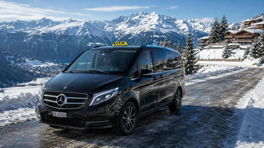 Taxi Mercedes Classe V noire sur la route de Verbier, chalets et Alpes valaisannes enneigées — transfert taxi Lausanne–Verbier