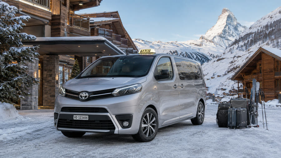Van Toyota Proace Verso TAXI 624 devant un chalet face au Cervin, valises et skis prêts à charger — skis et bagages compris