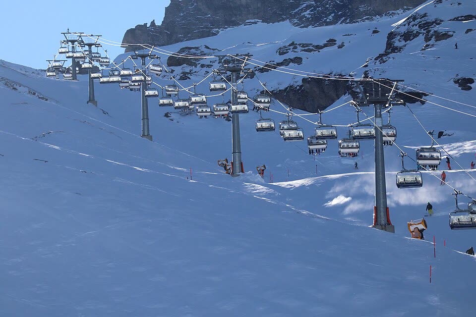 Télésiège et skieurs dans les Alpes suisses — transfert ski en taxi, skis et bagages compris